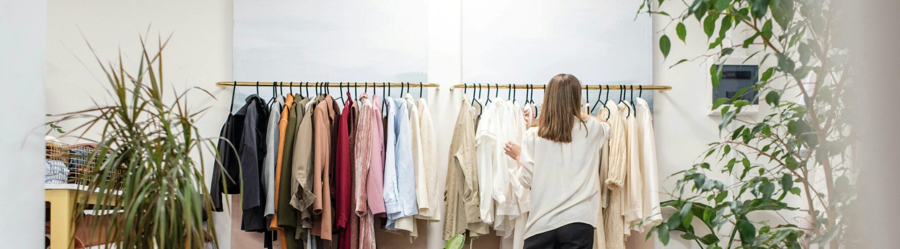 Una mujer coloca ropa en un perchero en una tienda de ropa