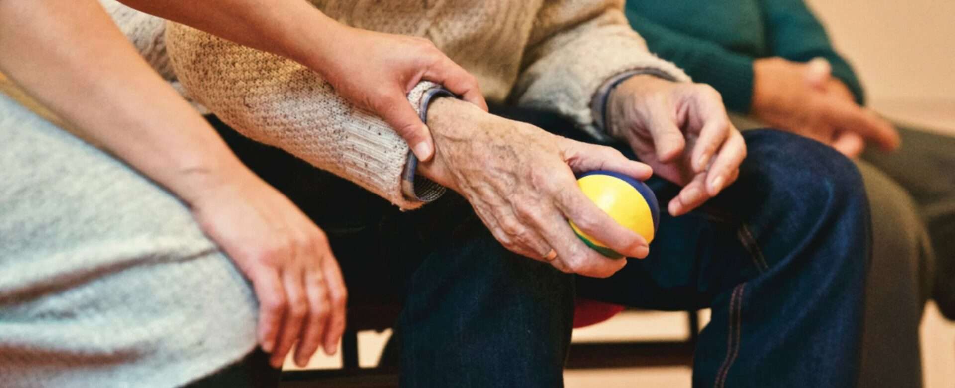 Una asistente social toca el brazo de un anciano durante una actividad en un centro de día